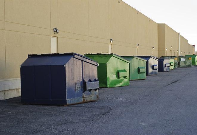 a pile of demolition waste sits beside a dumpster in a parking lot in Alpine